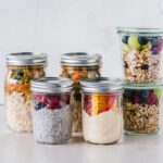 Close-up of healthy food jars containing granola, fruits, and yogurt.